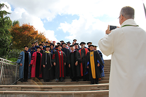 Admission counselor Rev. John Dreyer takes a photo of the faculty at the 2018 graduation service.