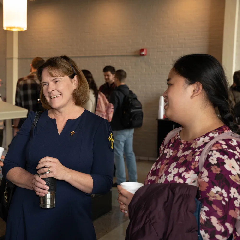 A woman and a student chat over coffee during a break.
